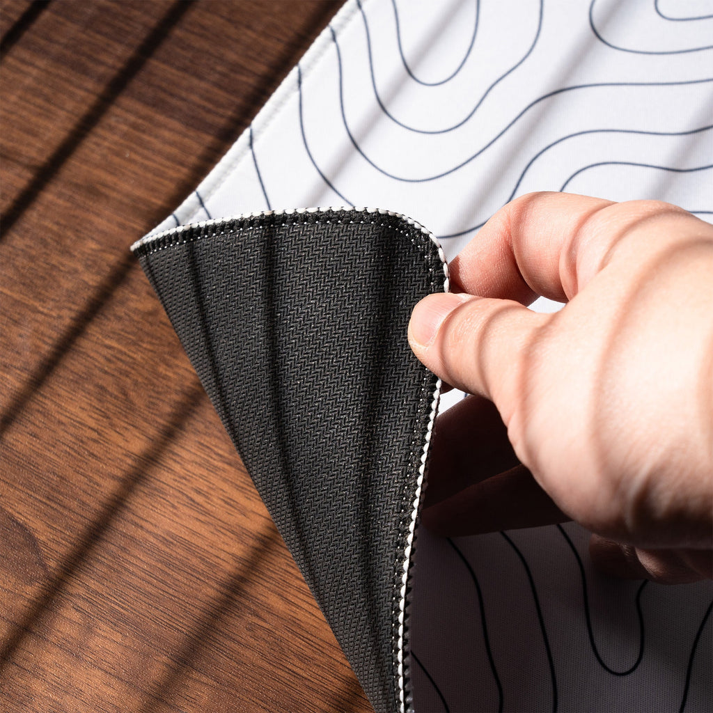 Rubber underside and stitched edge of an XVX Topographic desk mat